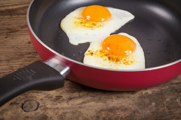 frying eggs in pan on old table