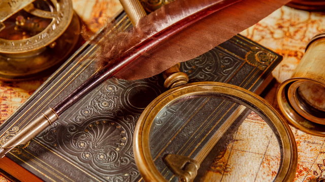 Vintage book, compass, telescope and a pocket watch lying on ancient world map in 1565.