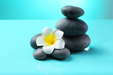 Obraz na płótnie Canvas Spa stones and flower on blue background