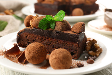 Chocolate balls, a piece of cake with walnut and mint on the table, close-up