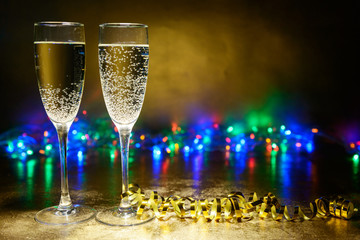 two glasses of champagne on a bright background with garlands