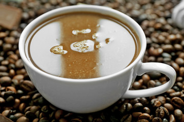 Cup of coffee with sweets and coffee beans closeup