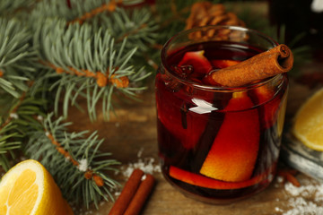 Mulled wine in glass bank with fruits on decorated wooden table, close up