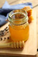 Glass jar with honey, honeycombs and nuts on wooden background