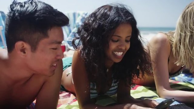 Close up portrait of young interracial friends lying on the beach 