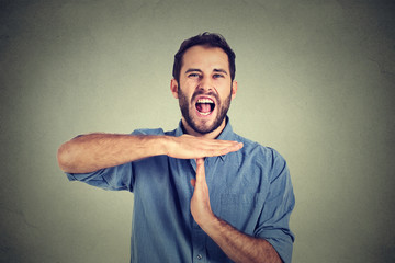 Young man showing time out hand gesture, frustrated screaming to stop