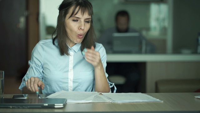 Sick businesswoman taking pill during work with documents in office
