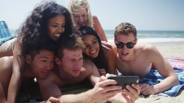 Group of six multi ethnic friends taking happy selfie on a sunny beach