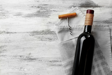 Wine with corkscrew on a light wooden background