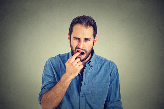 disgusted man with finger in mouth displeased with situation ready to throw up