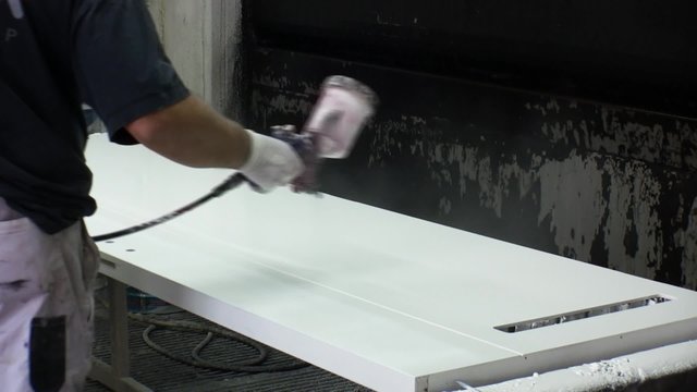 Worker  painting doors with spray gun in furniture factory.
