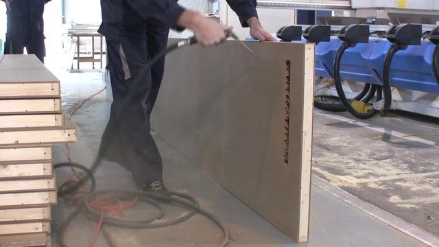 Worker blow out dust with high pressure air from new manufactured doors.
