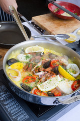 seafood paella being cooked in a silver frying pan
