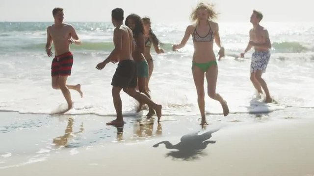 Happy Group of multi ethnic friends running along beach shore