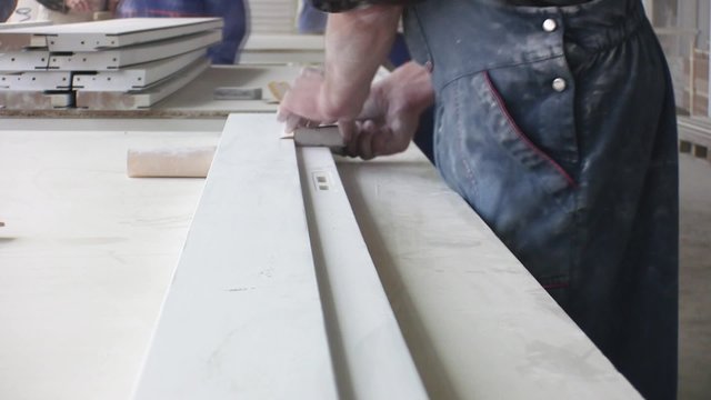 Worker using a power sander to smooth part of the doors frame.
