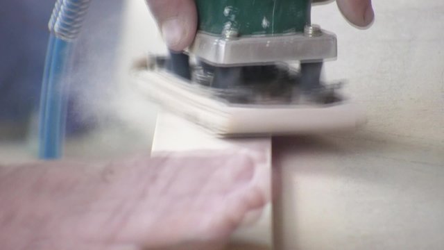 Worker using a power sander to smooth part of the doors frame.
