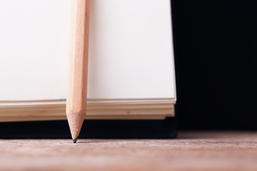 Wooden Pencil and Black Notebook on Wooden Table.