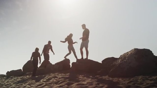 Group of friends exploring rocks at the beach