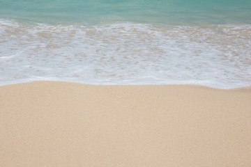 Fototapeta na wymiar Close up of sand, water and wave on seashore