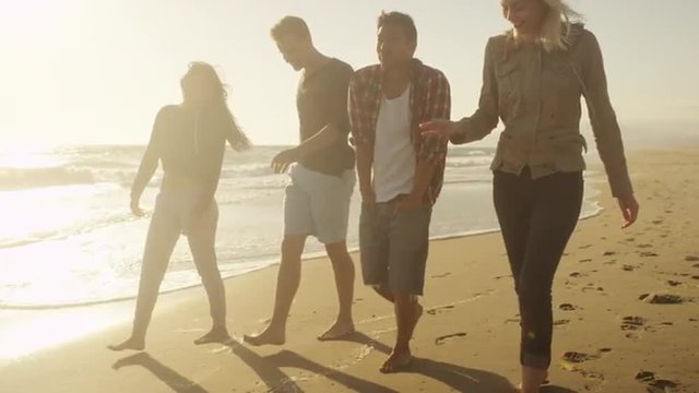 Group of friends walking on the beach together having fun