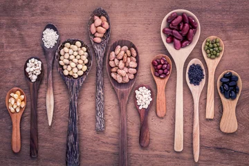 Poster Assortment of beans and lentils in wooden spoon on teak wood bac © kerdkanno
