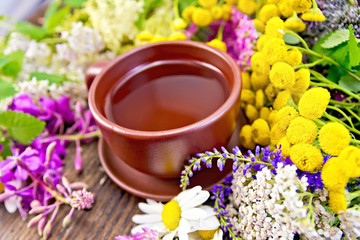 Obraz na płótnie Canvas Tea from wild flowers in clay cup on board
