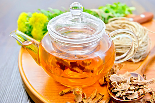 Tea of Rhodiola rosea in glass teapot on tray with spoon