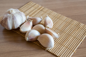 garlic cloves on makisu mat on wood texture