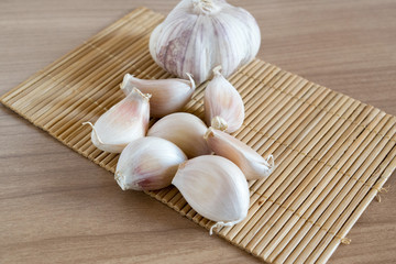 garlic cloves on makisu mat on wood texture