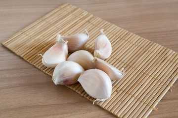 garlic cloves on makisu mat on wood texture