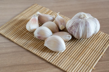 garlic cloves on makisu mat on wood texture