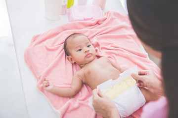 mother put on a baby diaper to her newborn