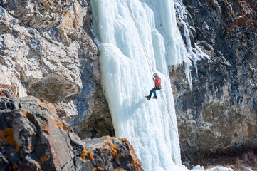girl mountaineer climbing a frozen waterfall and smiling