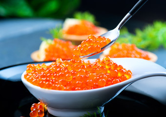 Caviar. Red caviar in spoon on a black background. Gourmet food closeup
