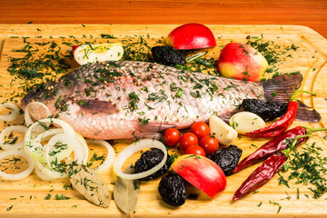 Fototapeta na wymiar Fresh carp with vegetables, fruits and spices on wooden board
