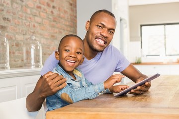 Cute son using tablet at desk with father