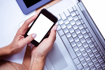 Businesswoman using her smartphone on desk