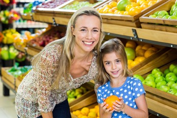 Mother with her daughter buying orange 