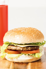 Hamburger with cheese and ingredients with a white background and timber board.