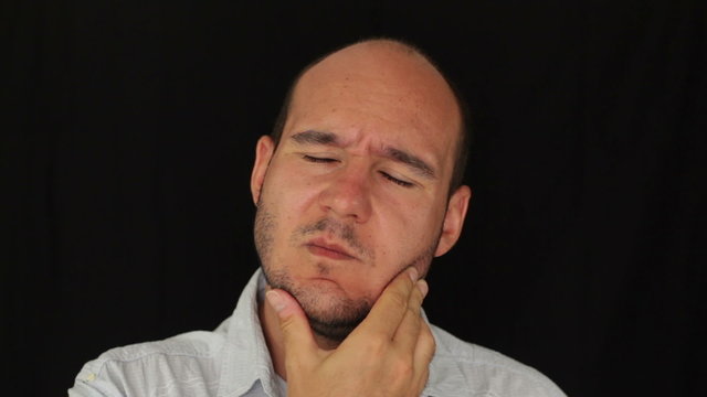 Unhappy man with toothache touching his face.