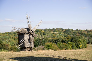 Fototapeta premium Windmill standing on the edge of the autumn forest