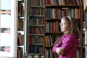 little girl with book in library