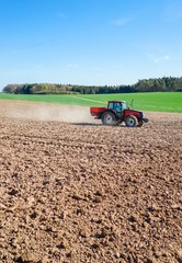 Roter Trecker auf einem Feld beim Kunstdünger streuen