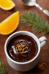 Delicious dessert from dark chocolate mousse with orange slice decorated citrus peel on rustic table