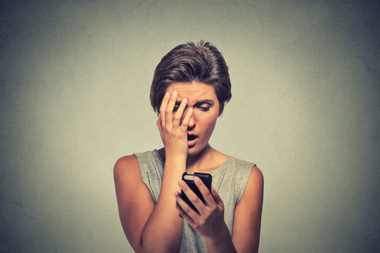 stressed woman holding cellphone disgusted shocked with message she received