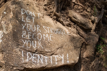 Don´t let your struggle become your identity. Creative motivation concept written on a rock.