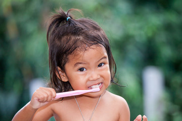 Child asian little girl brushing teeth on green background