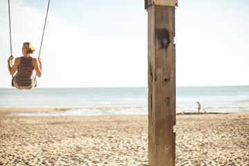 Junge blonde Frau schaukelt am Strand 4