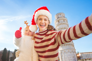 Obraz premium Mother in Christmas hat taking selfie with daughter in Pisa