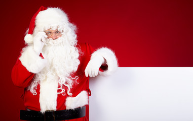Santa Claus pointing in white blank sign with smile,christmas 